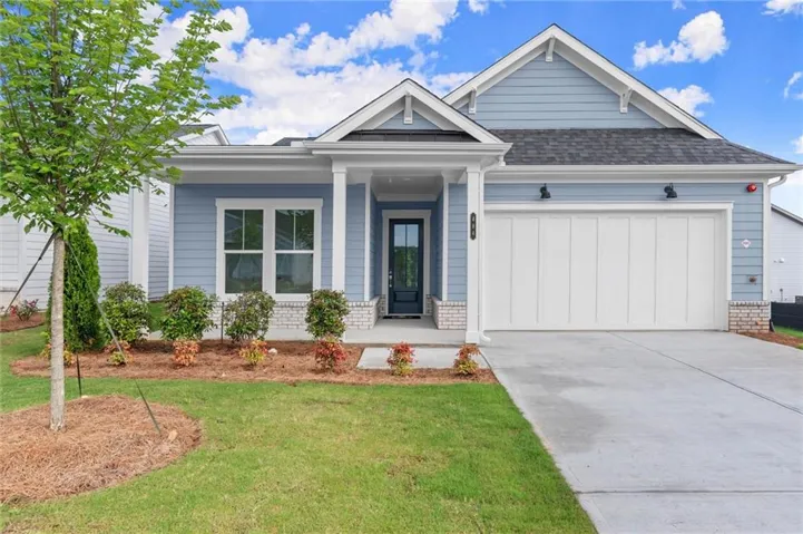 Light blue siding exterior with white trim, a single-car garage, covered entry with columns, and a well-maintained lawn with landscaping