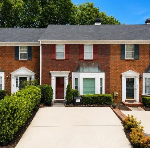 Brick townhome exterior with bay window, gabled entryways, and a private driveway
