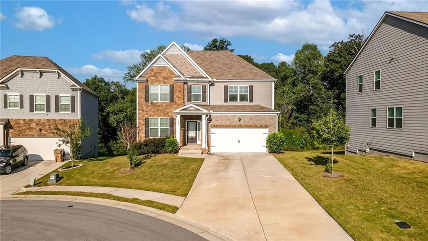 Two-story residence featuring a brick and siding facade, covered front entry, attached two-car garage, and a concrete driveway