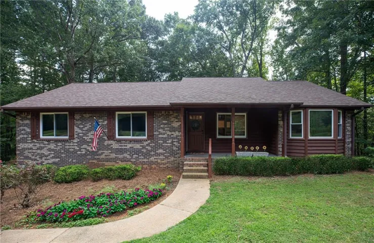 Ranch-style residence featuring a brick facade, wood-finish siding, and a covered front porch
