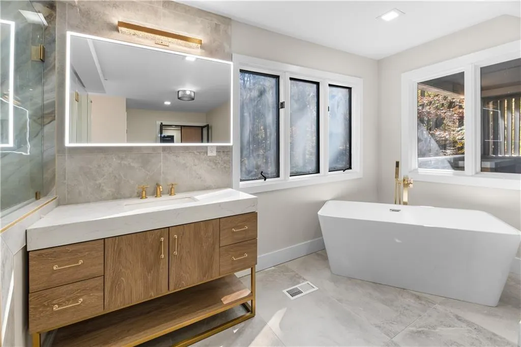 Full bathroom featuring vanity, a soaking tub, backsplash, and recessed lighting