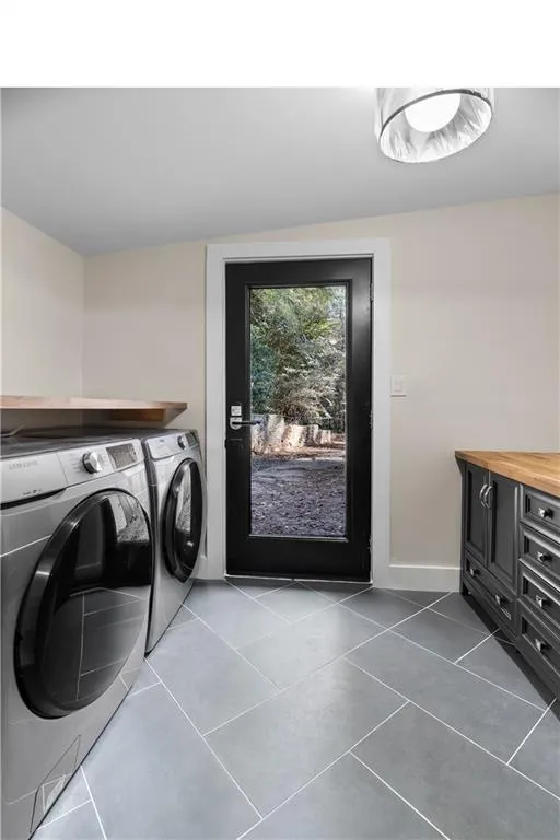 Laundry room with washer and clothes dryer and tile patterned floors