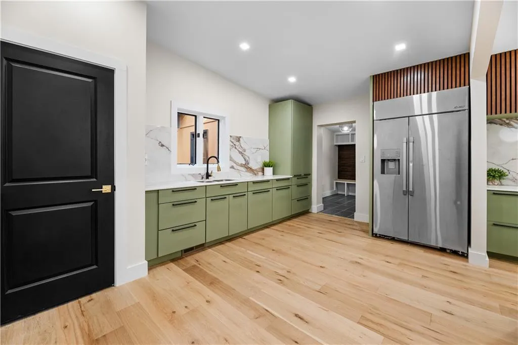 Kitchen featuring green cabinets, stainless steel fridge with ice dispenser, light countertops, light wood-type flooring, and recessed lighting