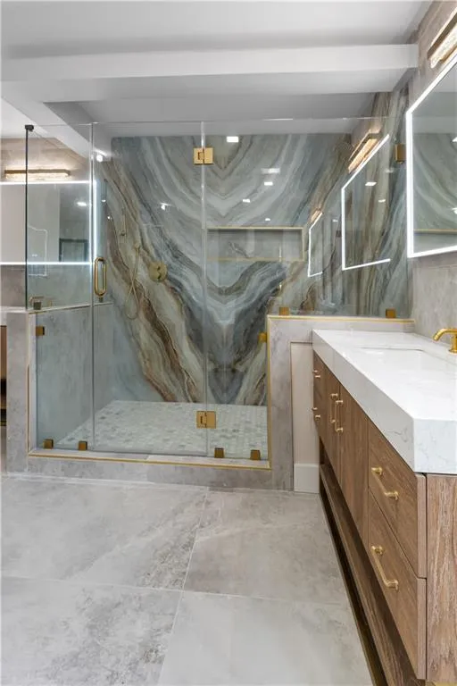 Full bathroom with tile walls, two vanities, and a marble finish shower