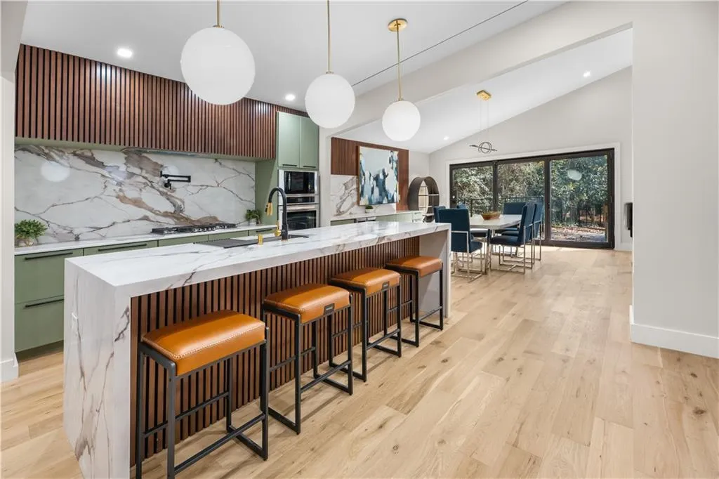 Living area featuring lofted ceiling, light wood-type flooring, a brick fireplace, a chandelier, and beverage cooler