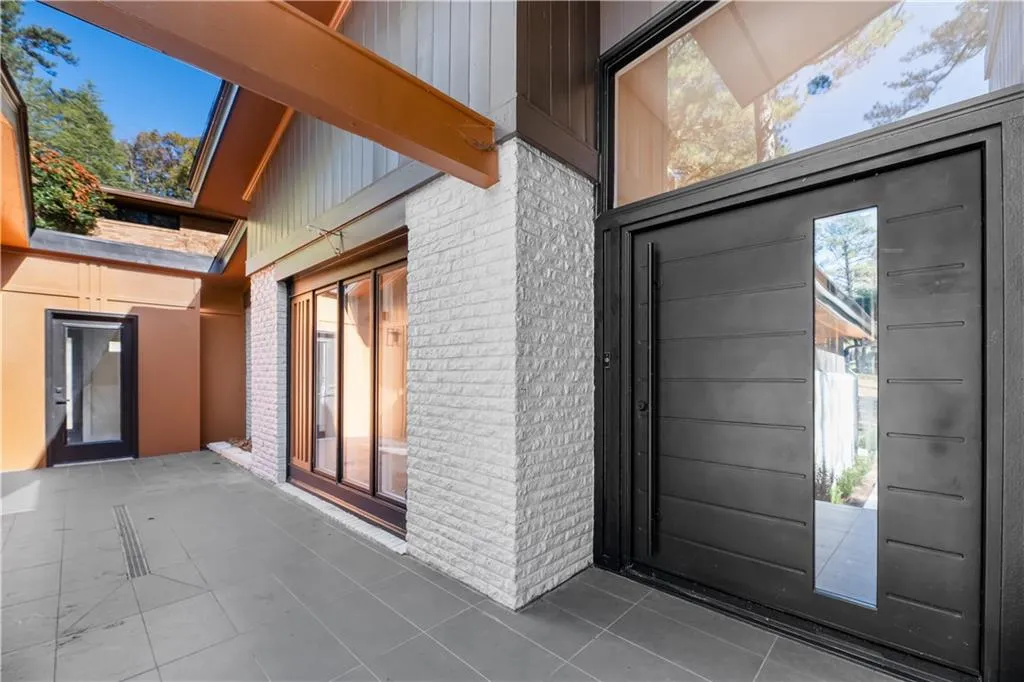 Property entrance featuring brick siding, board and batten siding, and a patio