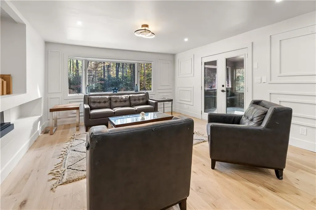 Living room with a decorative wall in basement french doors, light wood-type flooring, and recessed lighting