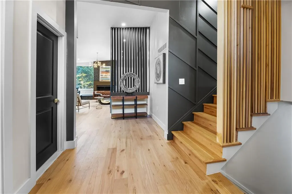 Hallway with a chandelier, light wood finished floors, and stairway