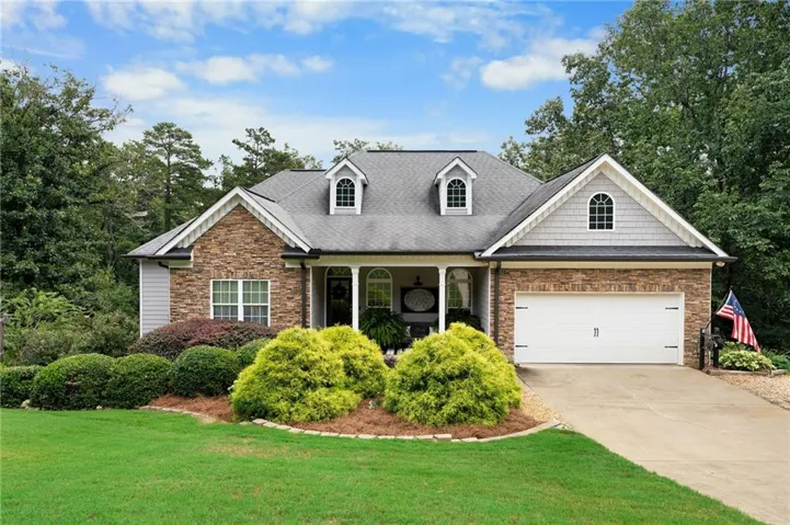 Brick and siding exterior with gabled roof dormers, arched entryway, and an attached two-car garage