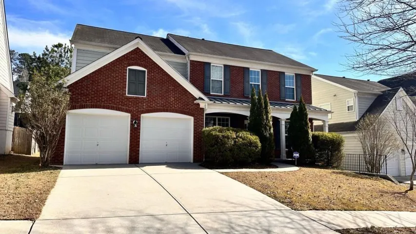Traditional style home featuring a brick and siding exterior, two-car garage with arched entrances, and a covered front porch