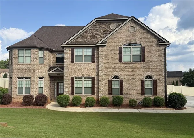 Traditional two-story brick residence featuring a multi-gabled roofline and dark wood shutters