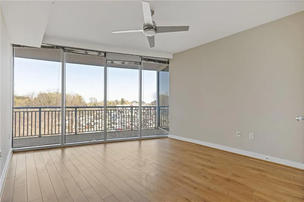 Unfurnished room with ceiling fan, wood finished floors, and expansive windows