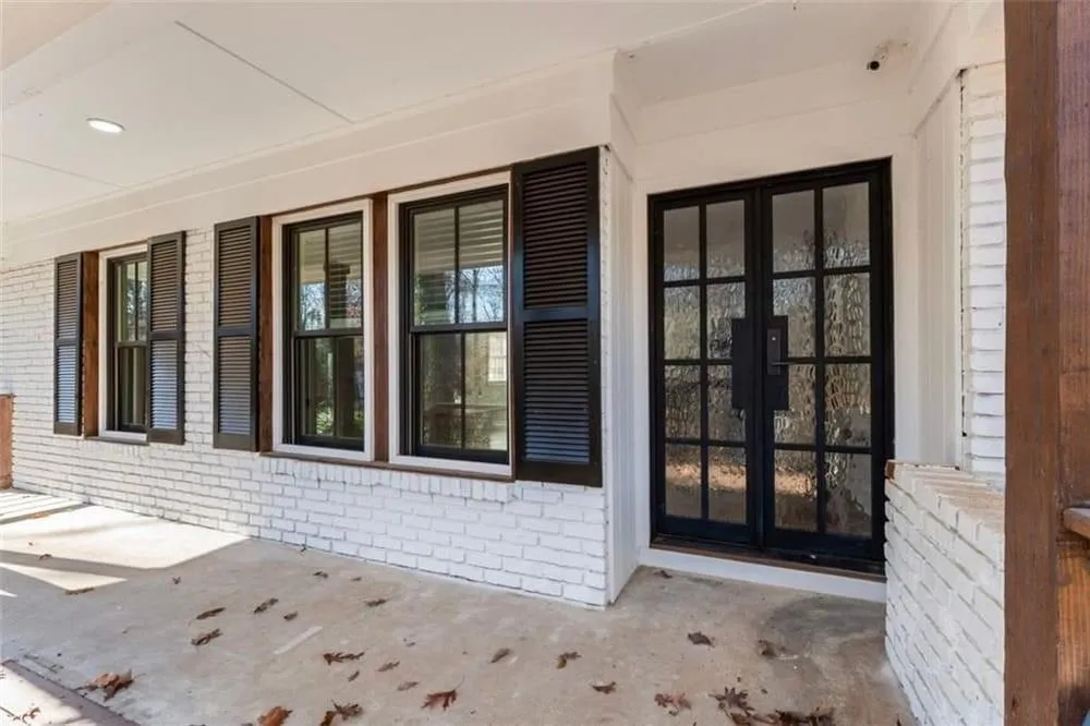 Doorway to property with brick siding and a porch