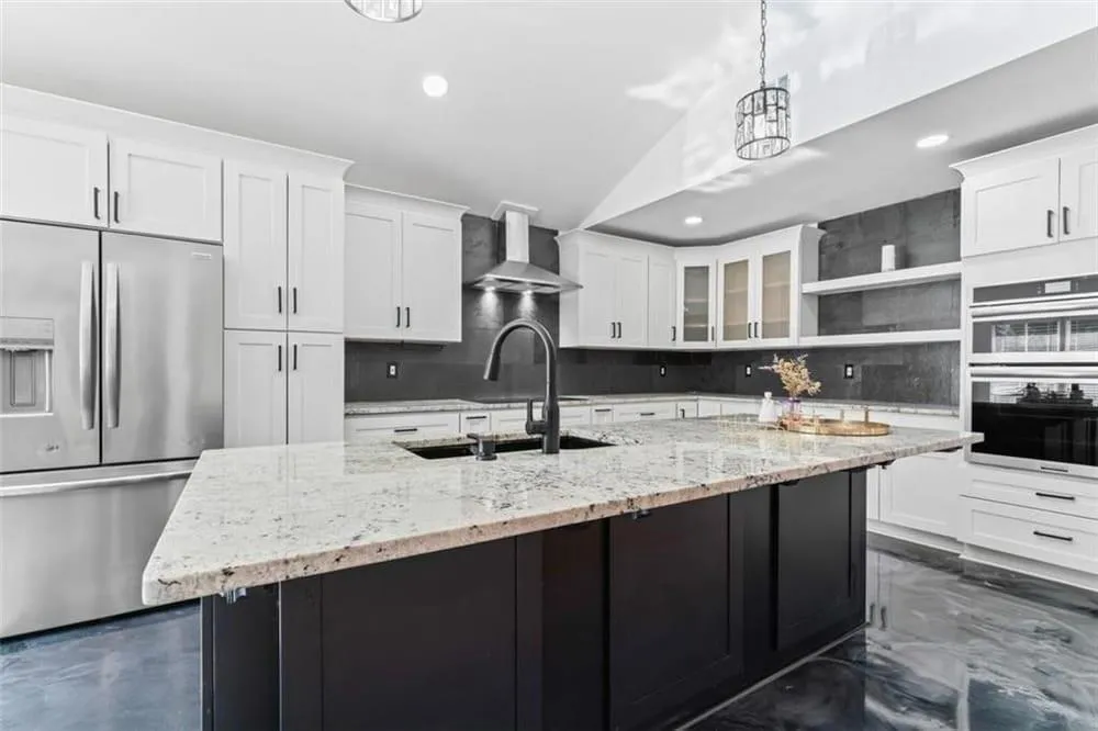 Kitchen featuring appliances with stainless steel finishes, white cabinetry, decorative light fixtures, vaulted ceiling, and recessed lighting