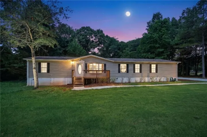 Single-story residence featuring light-colored siding and dark window shutters