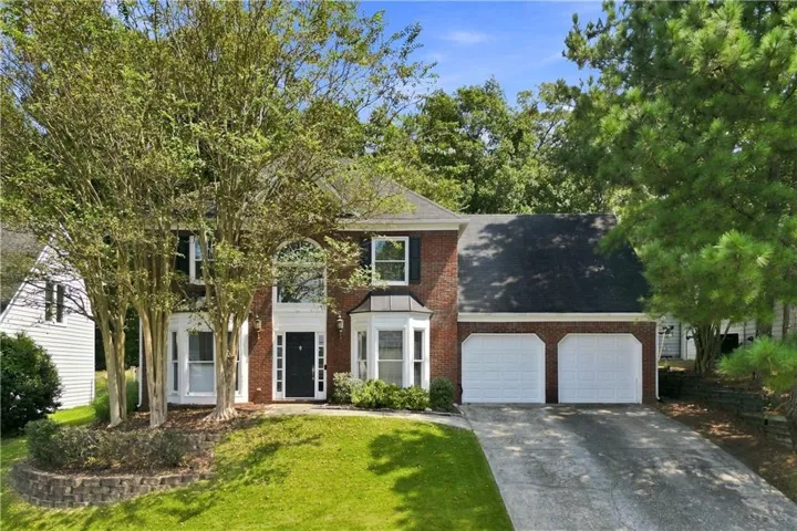 Brick facade with white trim, arched windows, and a two-car garage