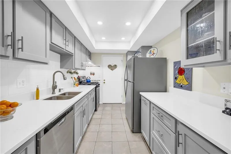 Kitchen with quartz countertops, gas range, stainless steel appliances, custom shaker style cabinets, tile floor