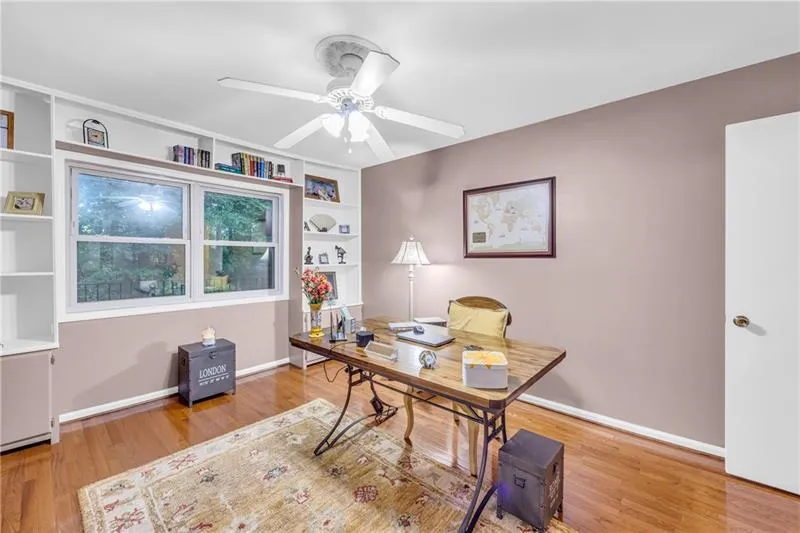 Office area featuring ceiling fan, built in shelves, and hardwood flooring