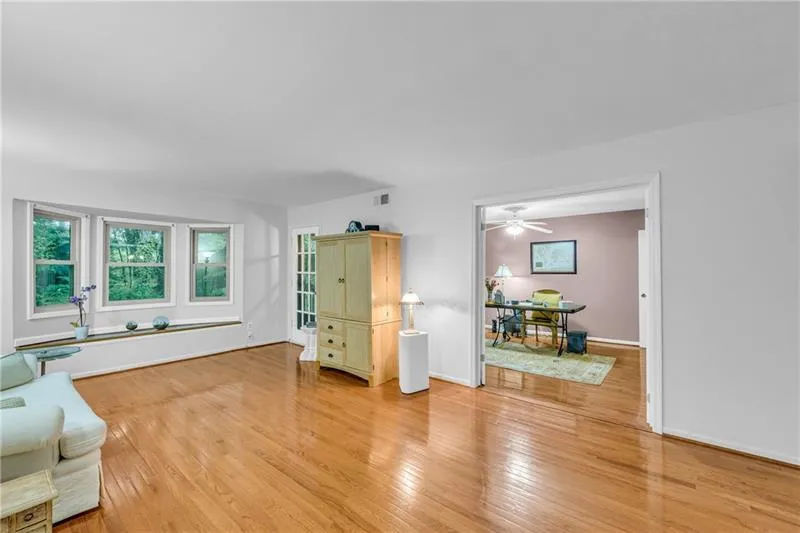 Spacious living area with bay window, hardwood floors, French doors to 3rd bedroom/office space & door to balcony access.