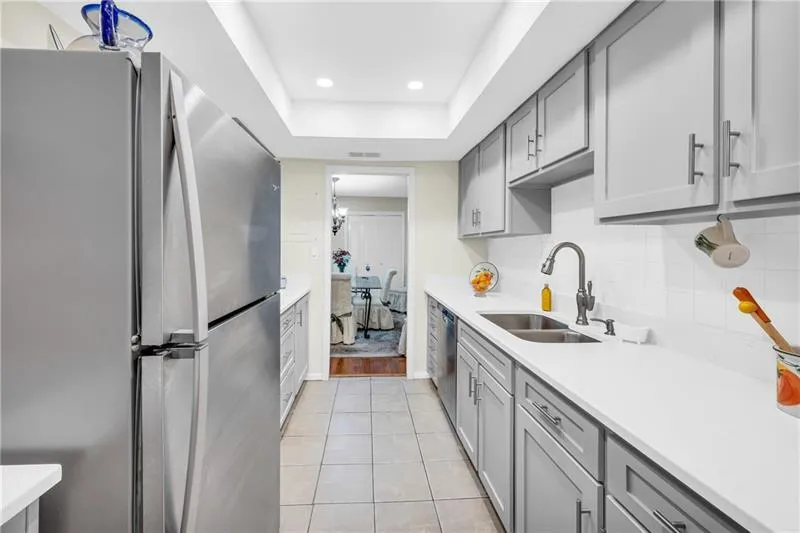 Kitchen featuring stainless steel appliances, custom gray cabinetry, recessed lighting and light tile floors.