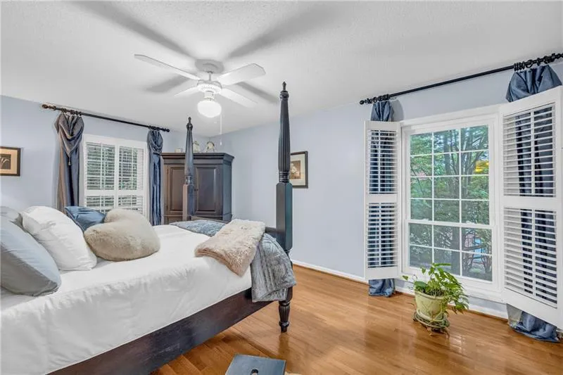 Bedroom featuring ceiling fan, hardwood floors, wooden privacy shutters