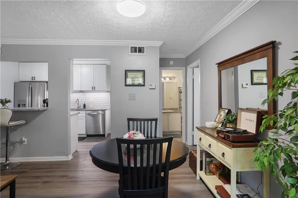 Dining space featuring sink, crown molding, a textured ceiling, and dark wood-type flooring