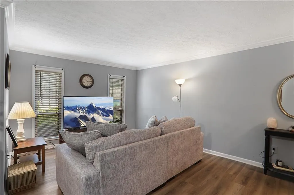 Living room with crown molding, a wealth of natural light, and dark wood-type flooring