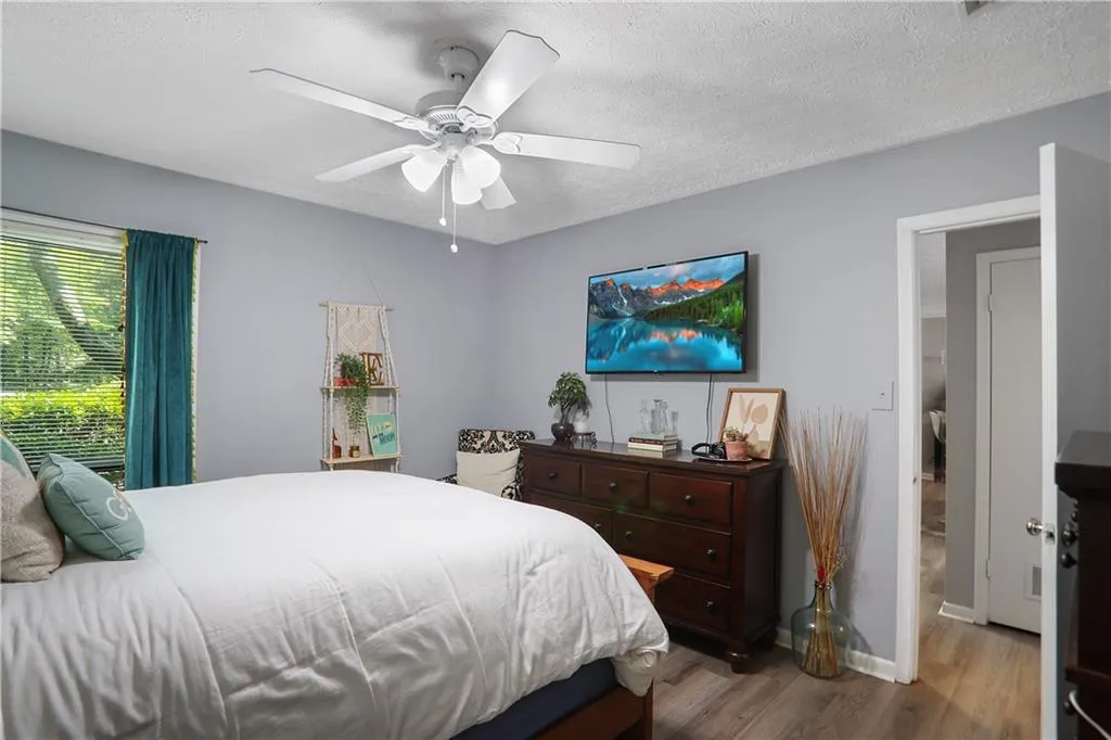 Bedroom with wood-type flooring, ceiling fan, and a textured ceiling