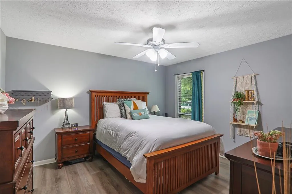 Bedroom featuring hardwood / wood-style flooring, ceiling fan, and a textured ceiling