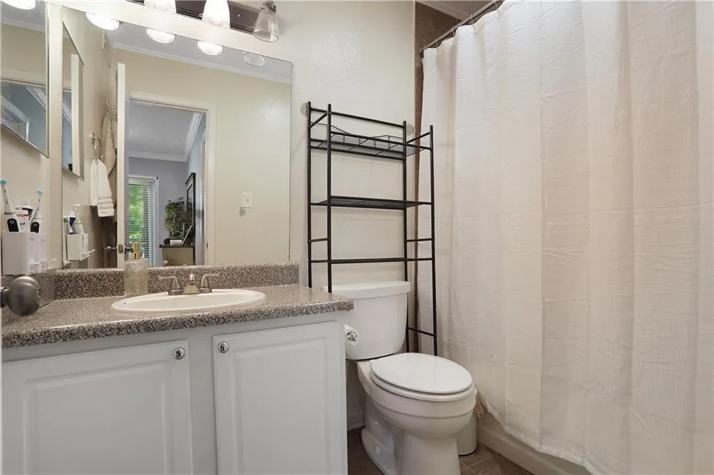 Bathroom with tile flooring, ornamental molding, toilet, and vanity