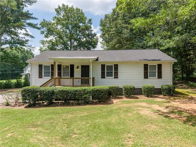 White siding exterior with a covered front porch featuring a wooden railing and steps