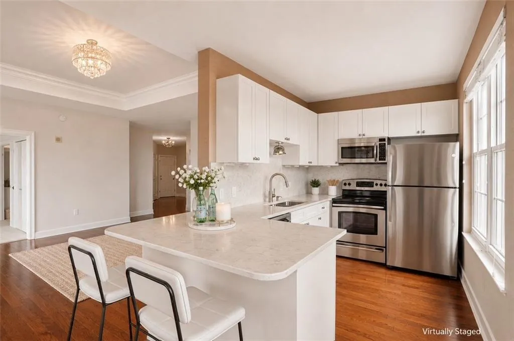 Kitchen featuring white cabinetry, stainless steel appliances, a stone-finish countertop island, and wood-finish flooring