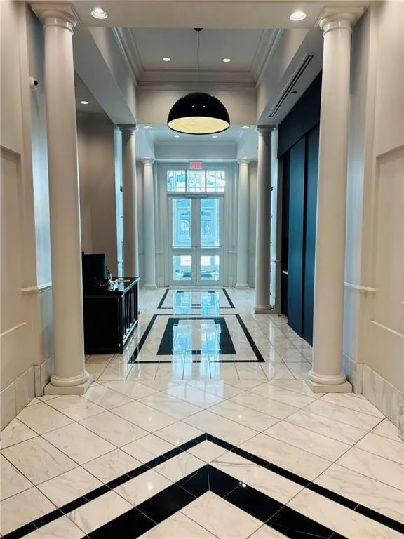 Hallway with decorative black and white tile flooring, recessed lighting, and wall sconces
