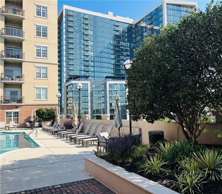 Outdoor heated, saltwater swimming poolwith integrated steps, surrounded by a concrete deck with lounge chairs and umbrellas