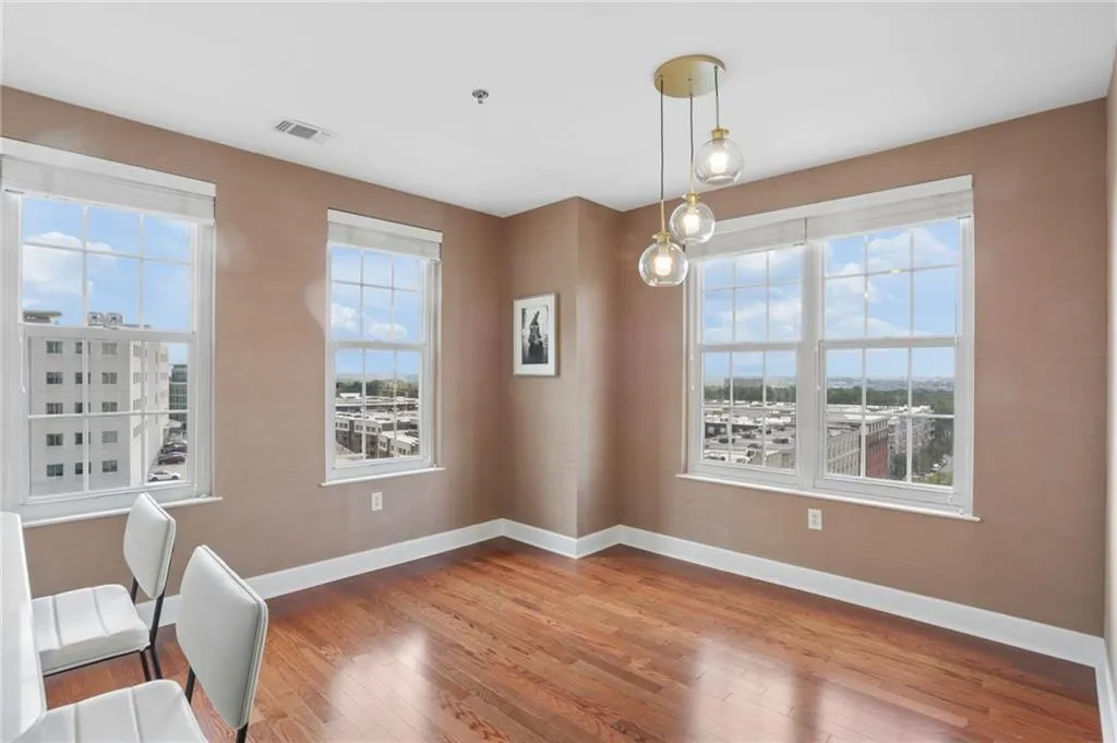 Hardwood flooring throughout, multiple large windows, flush-mounted ceiling light, and a modern pendant light fixture