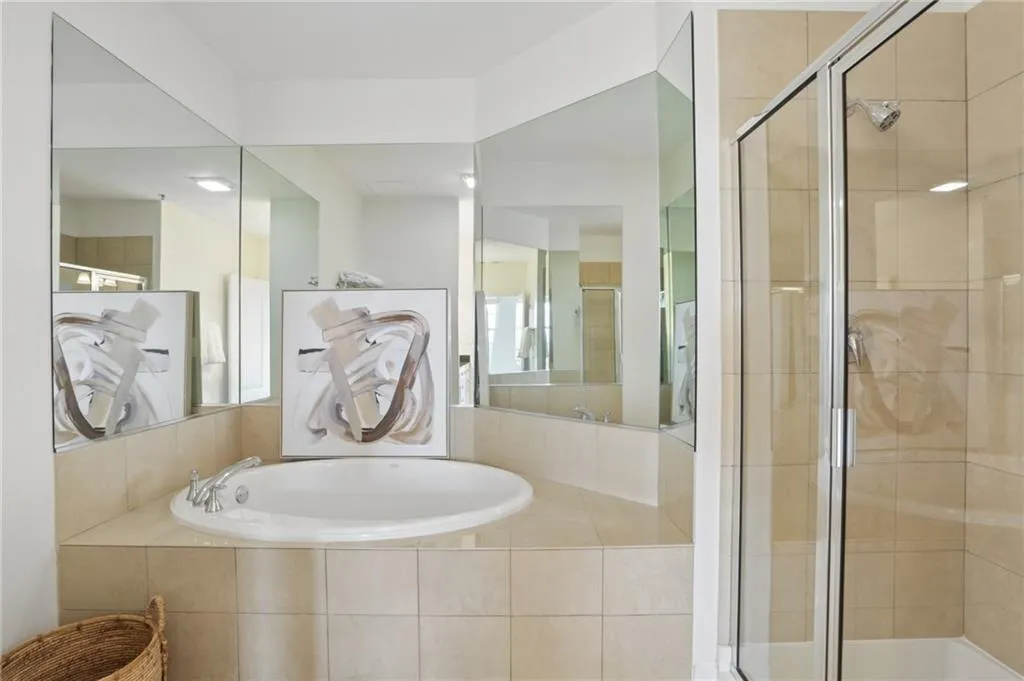Built-in soaking tub, tile surround, glass-enclosed shower, wall-mounted mirrors, and chrome fixtures