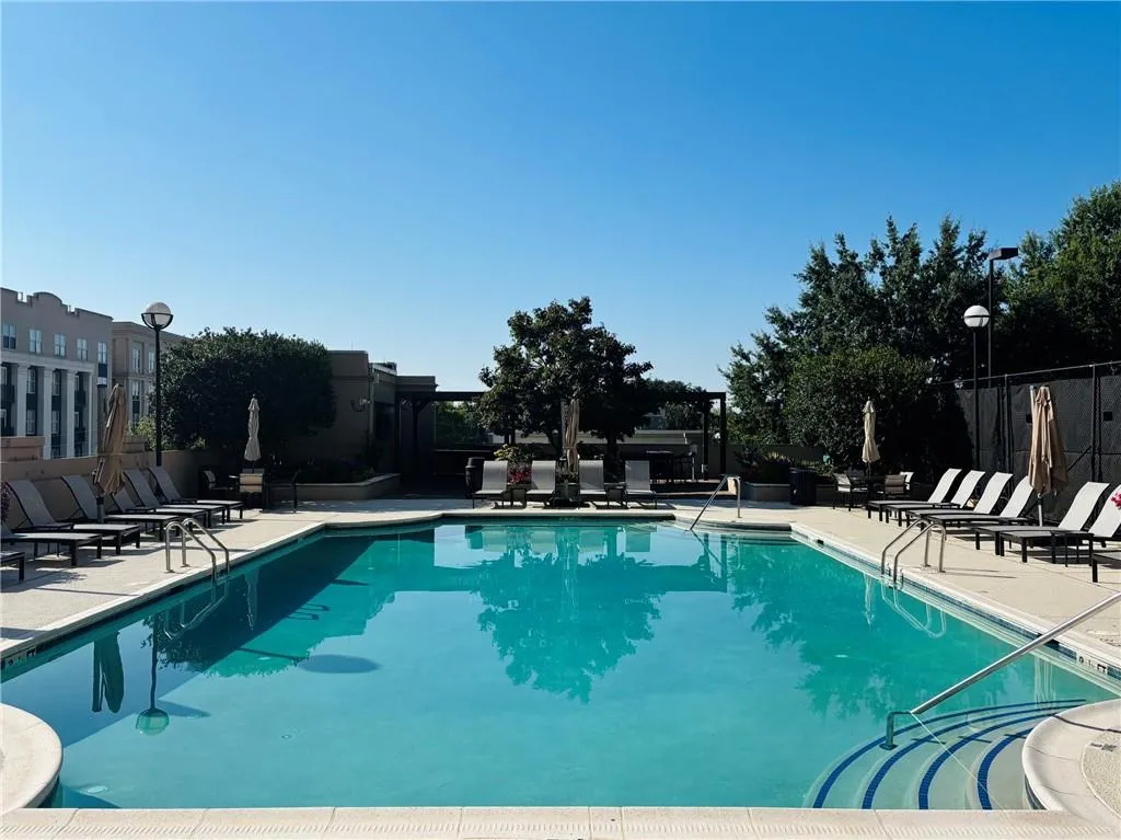 Gorgeous saltwater heated swimming pool with integrated steps, surrounding paved deck, and mature landscaping