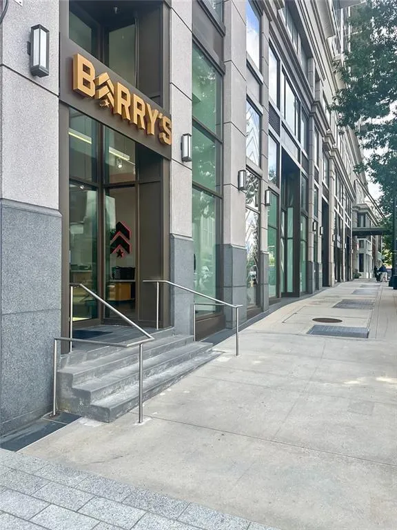 Stone facade with large storefront windows, exterior wall sconces, and a dedicated entrance with steps and handrails