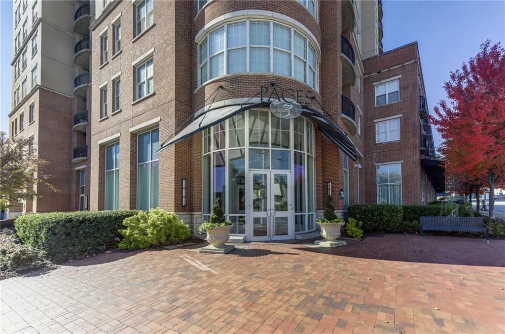 Brick building exterior with curved glass entry, arched awning, and extensive landscaping