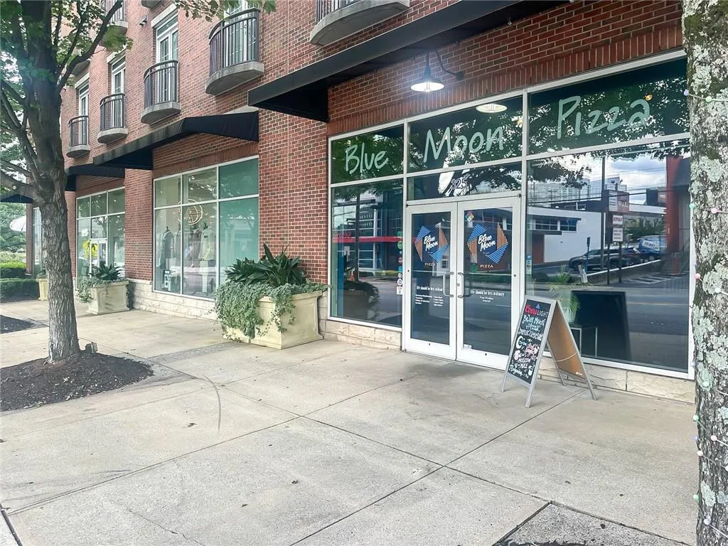 Ground-level retail space with extensive storefront windows, double-door entrance, and brick building facade