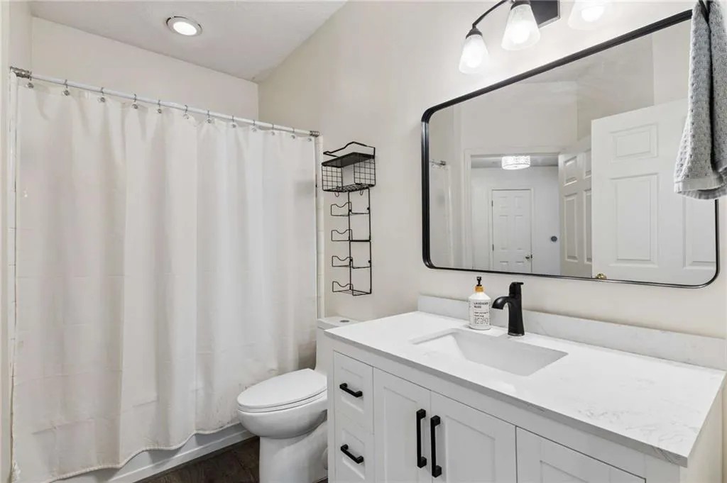 White vanity with black hardware, rectangular undermount sink, and stone-finish countertop