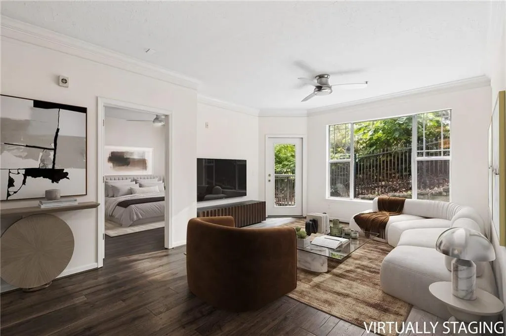 Spacious living area featuring wood-finish flooring, crown molding, and large windows