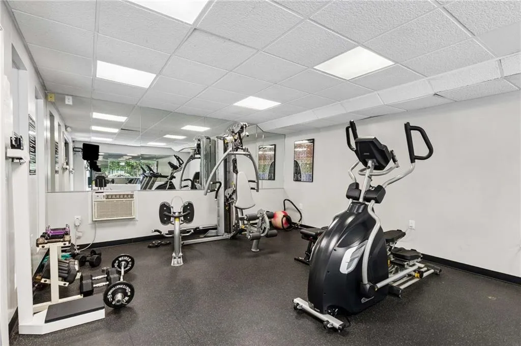 Rubber flooring, mirrored wall, recessed lighting, and wall-mounted air conditioning unit