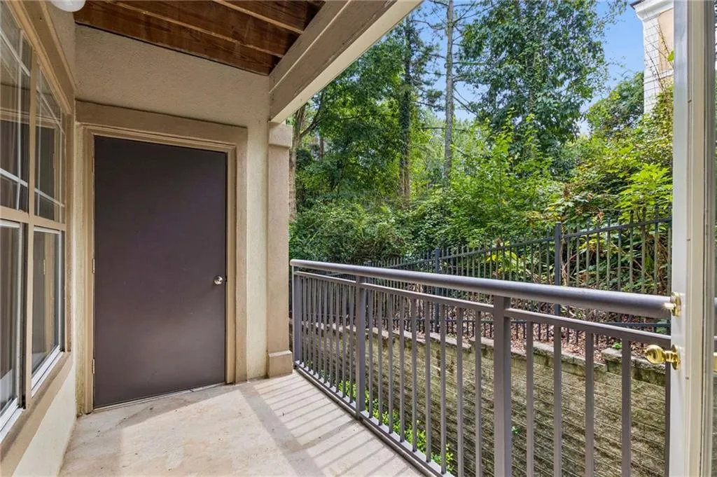 Private balcony with a concrete floor, metal railing, and a secure entry door