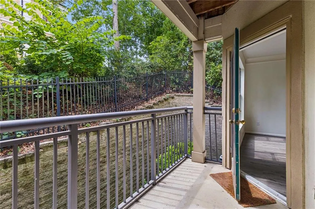 Covered patio with concrete flooring, supported by columns, and featuring a metal railing