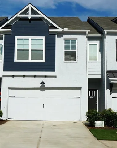 Two-story facade with painted brick and horizontal siding accents, a prominent front-facing gable, and a single-car garage with an exterior light fixture
