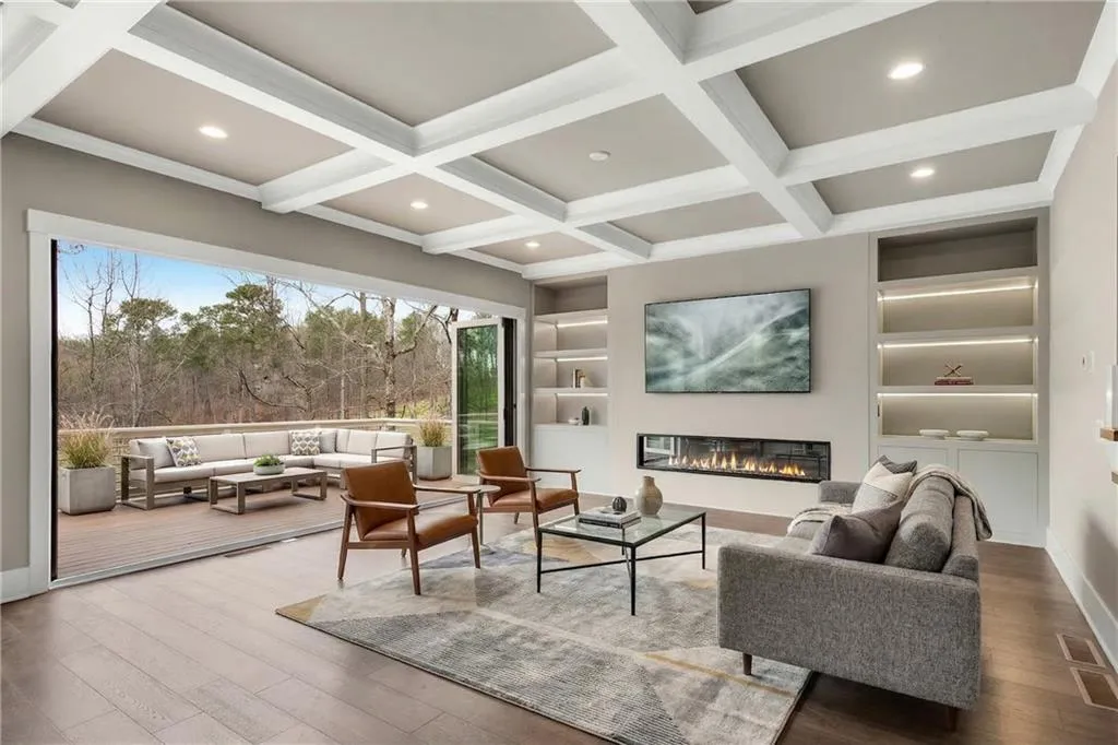 Living room with built in features, hardwood / wood-style flooring, a glass covered fireplace, coffered ceiling, and recessed lighting