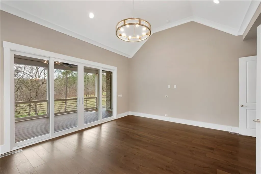 Spare room featuring hanging lights, dark wood-type flooring, lofted ceiling, and crown molding