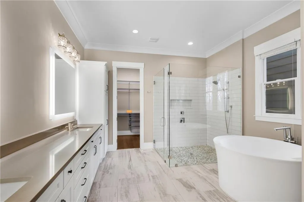 Full bath with a stall shower, double vanity, a freestanding bath, a walk in closet, and recessed lighting