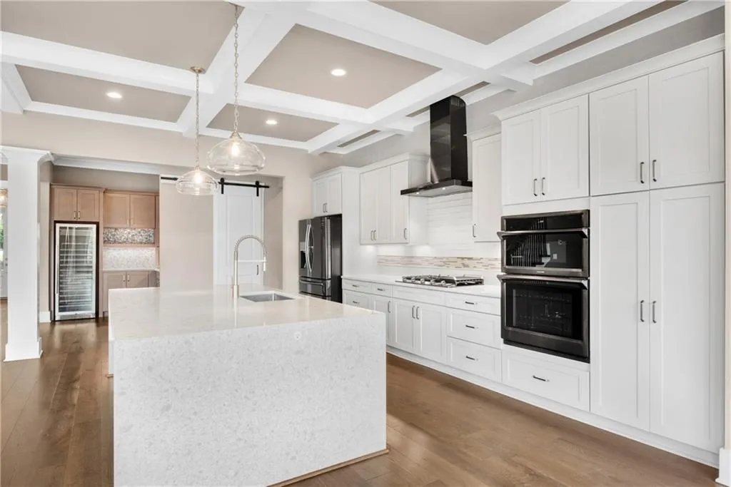 Kitchen with decorative backsplash, a barn door, wine cooler, coffered ceiling, and stainless steel appliances